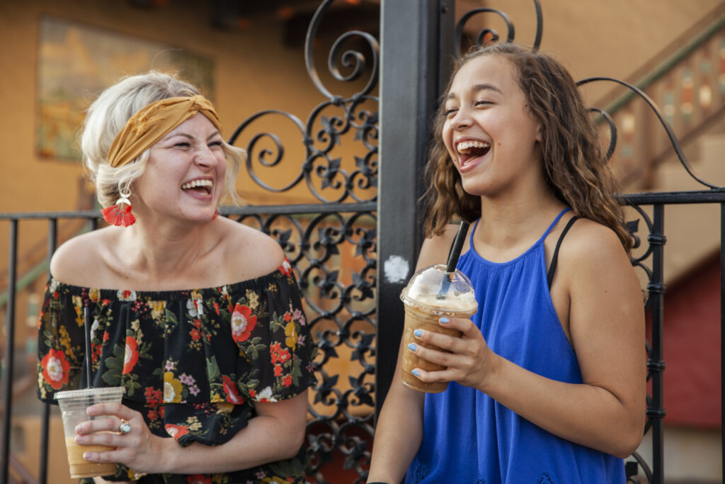 Big Sister and Little Sister laughing over iced coffees