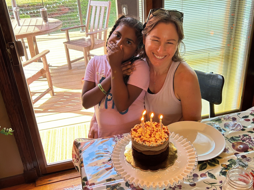 Big Sister and Little Sister seating at table with a birthday cake