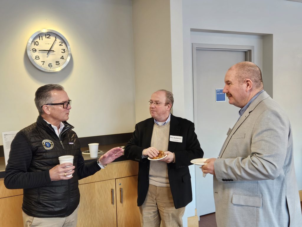 Three individuals chatting prior to the start of the presentation